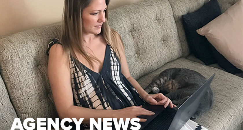 She on the couch with her computer next to her cat